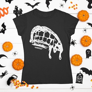 May include: A black t-shirt featuring a white graphic of dripping fangs. The shirt is surrounded by Halloween decorations, including bats, pumpkins, ghosts, and candy corn.