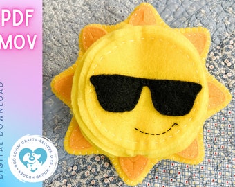 May include: A yellow felt sun with a smiling face and black sunglasses. The sun has orange felt rays.