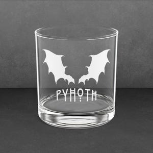 May include: A clear glass tumbler with a white etched design of two bat wings and the word "PYHOTH".
