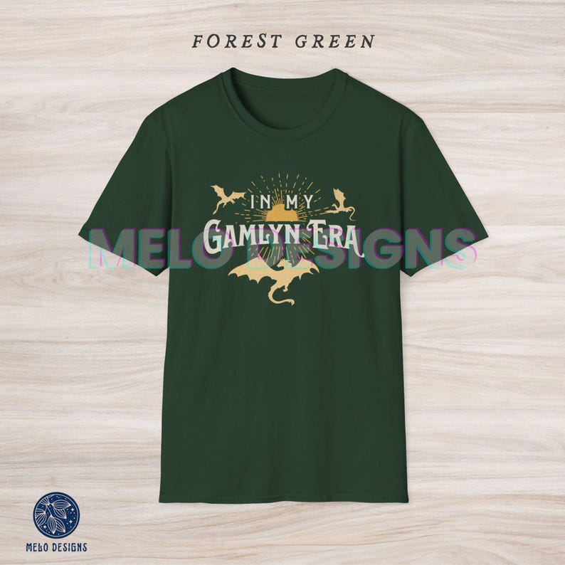 May include: Forest green t-shirt with a graphic design of three dragons flying around a sun with the text "In My Gamlyn Era".
