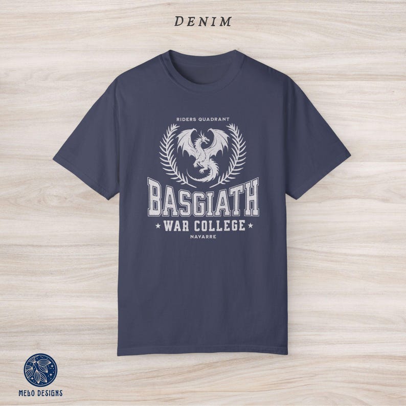 Puede incluir: Una camiseta azul marino con un gr&aacute;fico blanco de un drag&oacute;n y el texto "Riders Quadrant, Basgiath War College, Navarre".