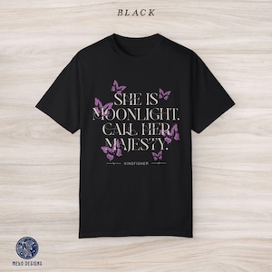 May include: Black t-shirt with a pink butterfly design and the text "She is moonlight. Call her majesty. Kingfisher"