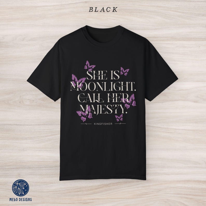 May include: Black t-shirt with a pink butterfly design and the text "She is moonlight. Call her majesty. Kingfisher"