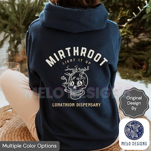 May include: Navy blue hoodie with a white graphic of a smoking skull and the text "MIRTHROOT LIGHT IT UP" and "LUNATHION DISPENSARY". The hoodie also has the text "MELO DESIGNS" and "Original Design By".