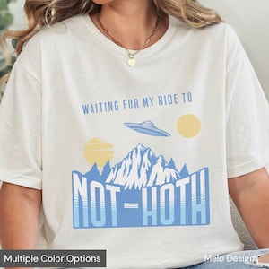 May include: White t-shirt with blue text that says "Waiting for my ride to Not-Hoth" with a blue spaceship and yellow suns above a blue mountain range.