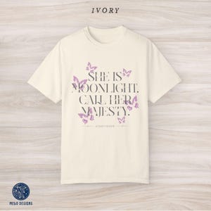 May include: Ivory t-shirt with a graphic print of butterflies and the text "She is moonlight. Call her majesty." with the word "KINGFISHER" underneath.