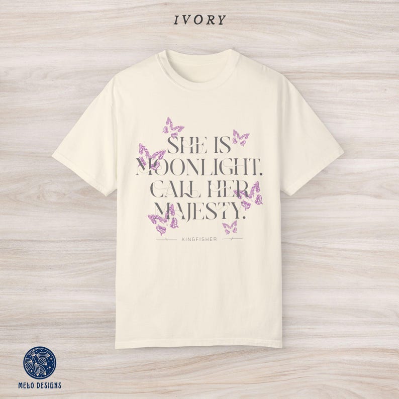 May include: Ivory t-shirt with a graphic print of butterflies and the text "She is moonlight. Call her majesty." with the word "KINGFISHER" underneath.