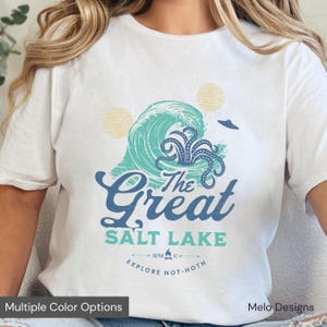 May include: White t-shirt with a blue and green graphic of a wave with an octopus inside. The text "The Great Salt Lake" is printed in blue below the wave. The text "Explore Not-Hoth" is printed in black below the main text.