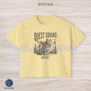 May include: A yellow cropped t-shirt with a graphic of a cat wearing a backpack and the text "Quest Squad" and "Broccoli".