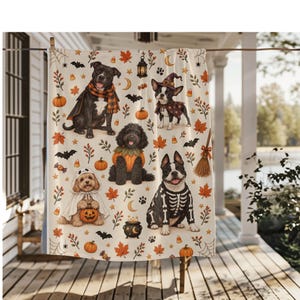 May include: A cream-coloured throw blanket featuring a repeating Halloween pattern of dogs in costumes, including a skeleton, a ghost, and a witch. The design includes orange pumpkins, autumn leaves, bats, candy corn, a lantern, and a black cauldron.