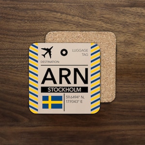 May include: Square coaster with a luggage tag design for Stockholm, Sweden. The coaster features the airport code ARN, the Swedish flag, and coordinates. The design includes a yellow and blue striped border and a cork backing.