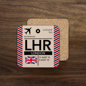 May include: A square coaster with a luggage tag design. The coaster features the text "LHR LONDON" with the Union Jack flag and coordinates. The design includes a red, white, and blue striped border and a small airplane icon.