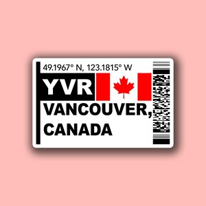 May include: A white sticker featuring the text "YVR VANCOUVER, CANADA" in black, with a Canadian flag and barcode. The flag shows a red maple leaf on a white background. Coordinates are also displayed.