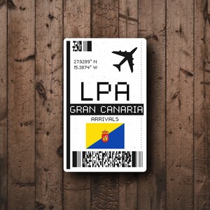 May include: A white airport arrival ticket with the code LPA, Gran Canaria, and the coordinates 27.9289° N 15.3874° W. The ticket also features a small airplane icon and the flag of the Canary Islands.