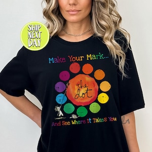 May include: Black t-shirt with the text "Make Your Mark... the dot And See Where It Takes You." The design features a colorful dot pattern. The shirt also has a "Ship Next Day" sticker.