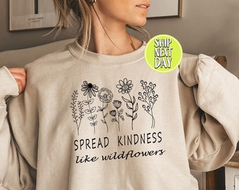 May include: A beige sweatshirt with a black graphic of wildflowers and the text "Spread Kindness like wildflowers".