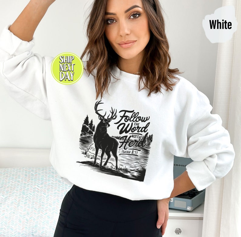 May include: White sweatshirt with a black graphic of a deer, trees, and the text "Follow the Word Not the Herd" and "Isaiah 8:11". The sweatshirt is a crew neck style.