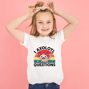 Pode incluir: Camiseta branca com um gr&aacute;fico retro de um axolotl com o texto "I axolotl questions".