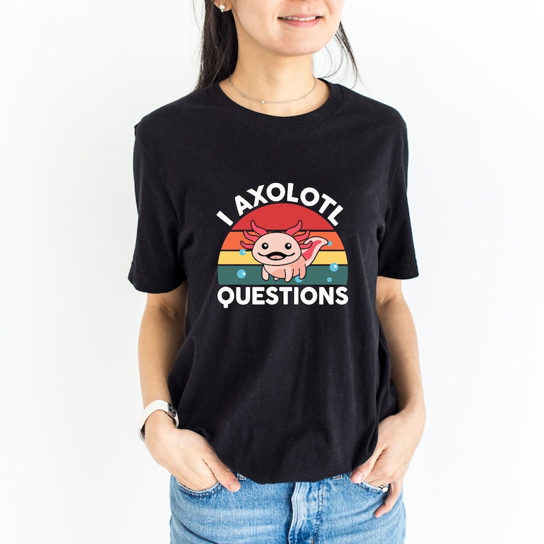 Pode incluir: Camiseta preta com um gr&aacute;fico retro de um axolotl com o texto "I axolotl questions".
