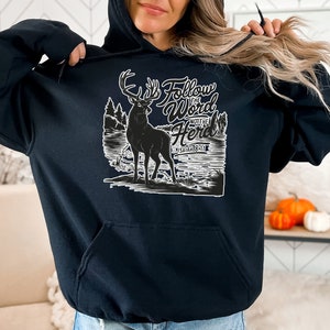May include: Black hoodie with a white graphic of a deer in a forest scene. Text on the hoodie reads "Follow the Word Not the Herd" and "Isaiah 8:19". The hoodie has a front pocket and a hood with a drawstring.