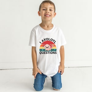Pode incluir: Uma camiseta branca com um gr&aacute;fico retr&ocirc; de um axolotl com o texto "I axolotl questions".