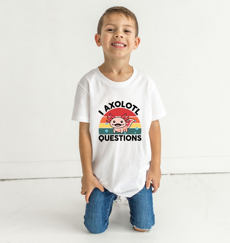 Pode incluir: Uma camiseta branca com um gr&aacute;fico retr&ocirc; de um axolotl com o texto "I axolotl questions".