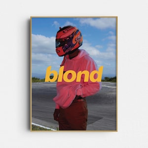 Puede incluir: Impresión artística enmarcada que muestra a una persona con un casco de carreras rojo y negro y una sudadera con capucha rosa. La palabra "blond" está impresa en amarillo. El fondo muestra un cielo azul y un circuito.