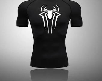Puede incluir: Camiseta negra de manga corta con un gráfico de araña blanca en la parte delantera.