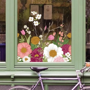 May include: A window with a floral design featuring pink, white, and yellow flowers. The window is set in a green frame, with a bicycle visible in the foreground. The flowers include peonies, tulips, and other blossoms.