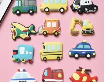 May include: A collection of colorful toy vehicles, including a green truck, yellow school bus, police car, airplane, orange truck, excavator, blue train, yellow school bus, blue taxi, police car, red fire truck, and a red helicopter.