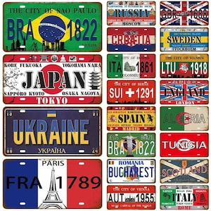 Puede incluir: Un conjunto de placas de matrícula metálicas de estilo vintage que representan varias ciudades y países. Las placas muestran banderas, nombres de ciudades y fechas históricas, como "1822". Las placas son rectangulares con un acabado envejecido.