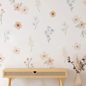 May include: A light-coloured wooden console table with a woven front panel and a vase of dried flowers. The wall behind the table is decorated with a floral pattern of peach, blue, and brown flowers.