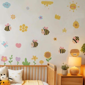 May include: A nursery wall decorated with colorful bee and flower decals. The design includes cartoon bees, flowers, hearts, and a sun. A wooden crib and nightstand with a lamp are in the foreground.