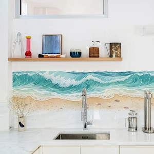 Puede incluir: Un protector contra salpicaduras de cocina con una pintura de acuarela de olas del océano rompiendo en una playa arenosa. La obra de arte es predominantemente en tonos turquesa y blanco, con una costa beige. Una estantería de madera arriba muestra objetos decorativos.