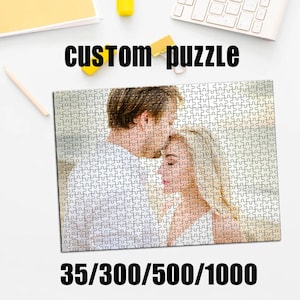 May include: A custom puzzle featuring a romantic image of a couple. The puzzle is made up of many small pieces, with the text "custom puzzle" at the top. The bottom of the puzzle has the numbers 35/300/500/1000.
