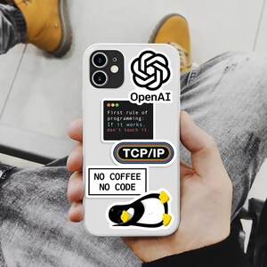 Op de afbeelding: Een witte smartphonehoesje versierd met stickers met een technisch thema. De stickers bevatten het OpenAI-logo, "TCP/IP" en de tekst "First rule of programming: If it works, don't touch it." Een pingu&iuml;nsticker en "NO COFFEE NO CODE" zijn ook zichtbaar.