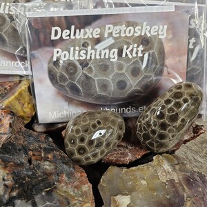 May include: Deluxe Petoskey Polishing Kit with polished Petoskey stones. The kit includes a clear plastic bag with the words "Deluxe Petoskey Polishing Kit" printed on the front. The stones are gray and brown with a unique pattern.