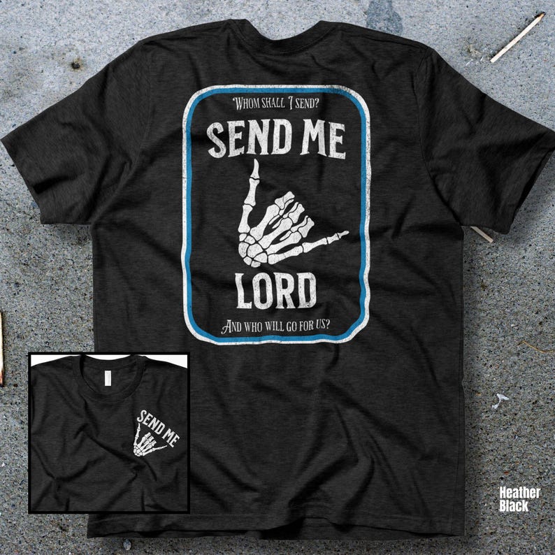 Puede incluir: Camiseta negra jaspeada con un dise&ntilde;o blanco y azul. El dise&ntilde;o presenta el texto "SEND ME LORD" con un gesto de mano de esqueleto. Tambi&eacute;n tiene el texto "WHOM SHALL I SEND? AND WHO WILL GO FOR US?"