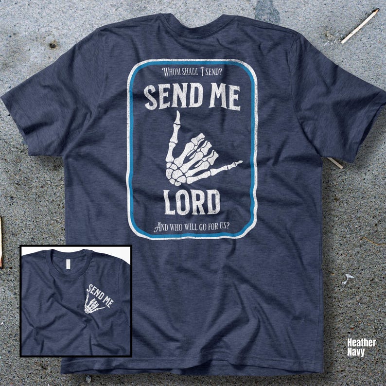 Puede incluir: Camiseta azul marino jaspeada con un gr&aacute;fico blanco y azul. El gr&aacute;fico presenta el texto "SEND ME LORD" con un gesto de mano de esqueleto. La camiseta tambi&eacute;n incluye el texto "WHOM SHALL I SEND? AND WHO WILL GO FOR US?"