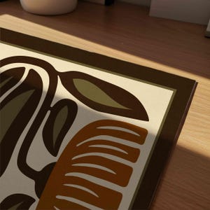 May include: A rectangular decorative mat with a retro design. The mat features a cream-colored background with brown, olive green, and orange abstract shapes and a dark brown border. The design includes leaf and curved shapes.