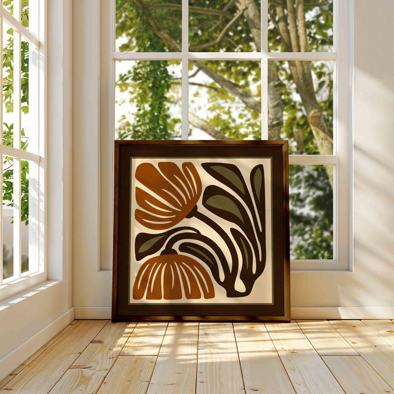 May include: A framed art print featuring a stylized floral design. The artwork showcases two large, rust-colored flowers with cream-colored petals and dark brown and olive green leaves against a cream background. The frame is dark brown.