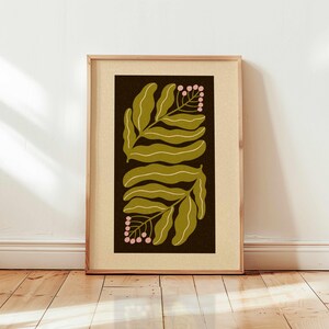 Pu&ograve; includere: Stampa artistica incorniciata con un design botanico. L'opera presenta due serie di foglie verde oliva con dettagli bianchi, su uno sfondo marrone scuro. Sono inclusi anche piccoli grappoli di bacche rosa. La stampa &egrave; racchiusa in una cornice di legno marrone chiaro.