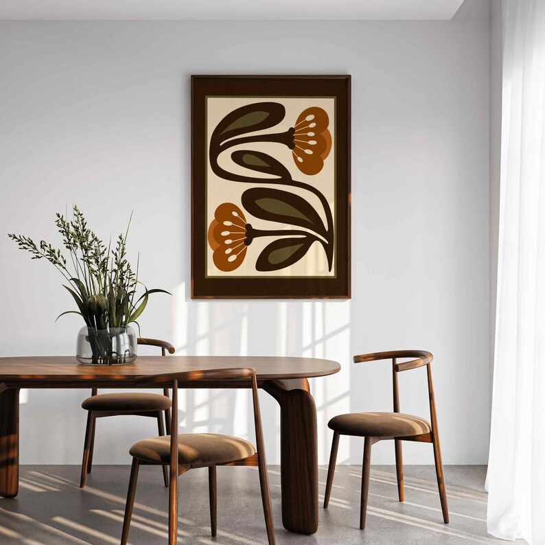 Puede incluir: Un cuadro enmarcado con dos flores estilizadas en tonos marr&oacute;n y naranja sobre un fondo crema. La obra de arte se presenta en un marco de madera marr&oacute;n oscuro, ideal para la decoraci&oacute;n del hogar.