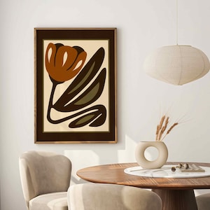 K&ouml;nnte beinhalten: Gerahmter Kunstdruck mit einer stilisierten Blume in Braun-, Olivgr&uuml;n- und Beiget&ouml;nen. Das Kunstwerk wird in einem dunkelbraunen Holzrahmen pr&auml;sentiert. Das Bild ist Teil einer Wohnkultur, mit einem runden Holztisch und St&uuml;hlen.