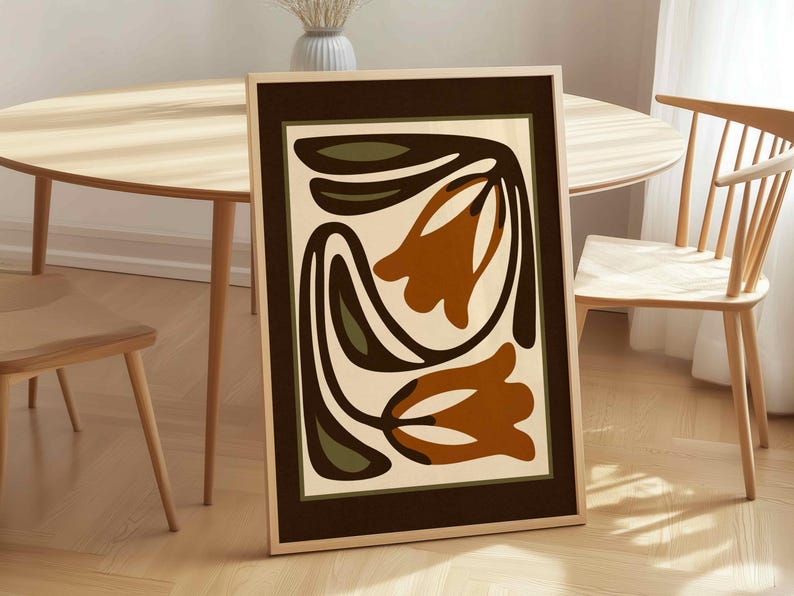 May include: Framed art print featuring a stylized floral design. The artwork showcases two orange-brown tulip-like shapes with dark green and brown accents against a cream background. The print is encased in a dark brown frame, adding a touch of elegance.