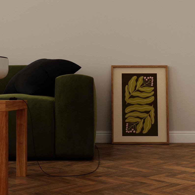 Pu&ograve; includere: Una stampa botanica incorniciata con foglie verde oliva e bacche rosa su sfondo scuro. L'opera d'arte &egrave; in una cornice di legno chiaro, appoggiata a una parete bianca. La stampa &egrave; accanto a un divano verde.