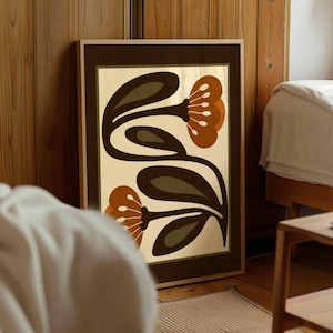 Puede incluir: Un estampado art&iacute;stico enmarcado con un dise&ntilde;o floral retro. La obra de arte muestra flores estilizadas en tonos marr&oacute;n, naranja y verde sobre un fondo crema. La impresi&oacute;n est&aacute; encerrada en un marco de madera con un borde marr&oacute;n oscuro, adecuado para la decoraci&oacute;n del hogar.