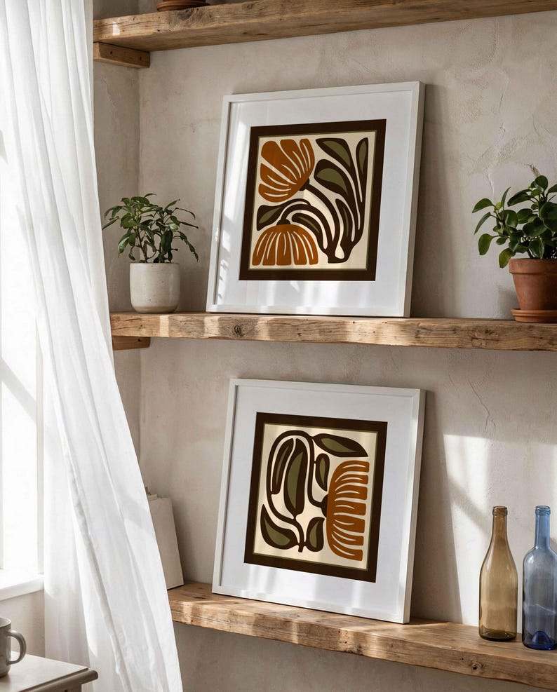 May include: Two framed floral art prints with white borders and brown and olive green designs. The prints are displayed on a rustic wooden shelf, alongside potted plants and decorative bottles. The artwork features abstract botanical illustrations.