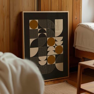 Può includere: Un'opera d'arte da parete rettangolare incorniciata che presenta una griglia di forme geometriche tra cui cerchi, semicerchi e quadrati. Il design utilizza una tavolozza di colori grigio scuro, giallo senape e bianco sporco.