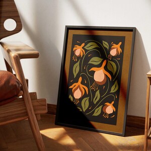 K&ouml;nnte beinhalten: Ein gerahmter Druck mit einem stilisierten Blumendesign mit orangefarbenen und rosafarbenen Blumen auf einem dunkelgr&uuml;nen Hintergrund. Der Rahmen ist schwarz mit einer braunen Passepartout.